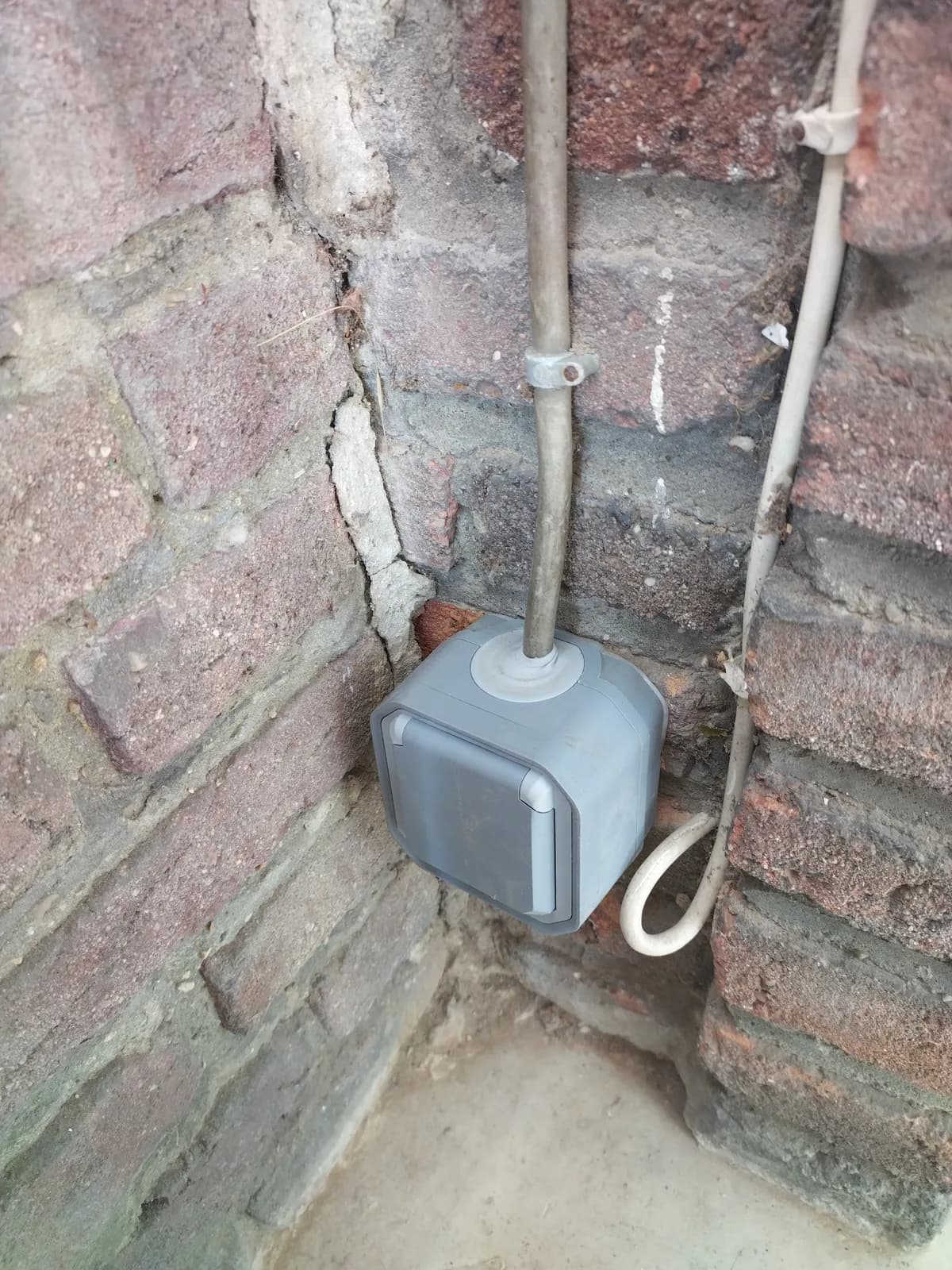 Boîtier de dérivation étanche posé en extérieur sur mur de brique